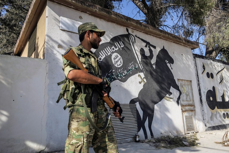 A Free Syrian Army fighter stands in front of a painting left by Islamic State militants in Jarablus, Syria, Wednesday, Aug. 31, 2016. (AP Photo)