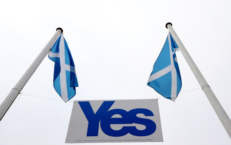 A pair of Saltire's fly above a Yes sign in Eyemouth, Scotland, Tueday, Sept. 16, 2014. The two sides in Scotland's independence debate are scrambling to convert undecided voters, with just two days to go until a referendum on separation. Anti-independence campaigners are pushing home their message that a 