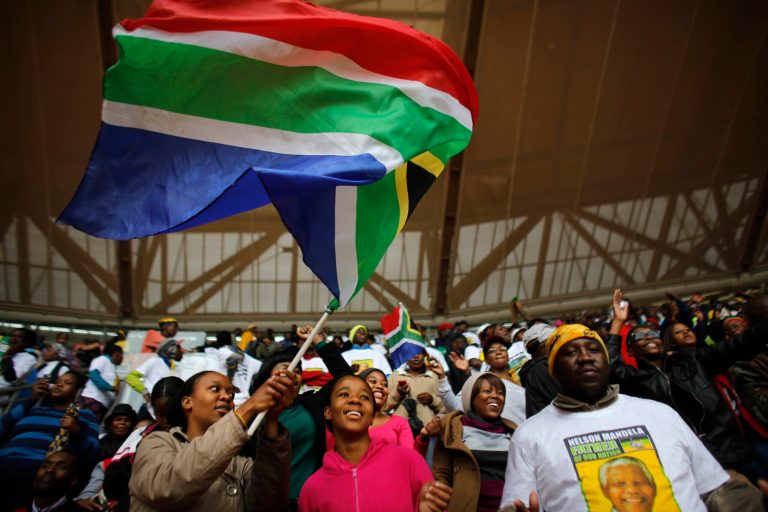 A woman waves a South African national flag ahead of the memorial service for former South African president Nelson Mandela at the FNB Stadium in Soweto, near Johannesburg, South Africa, Tuesday. (AP Photo/Markus Schreiber)