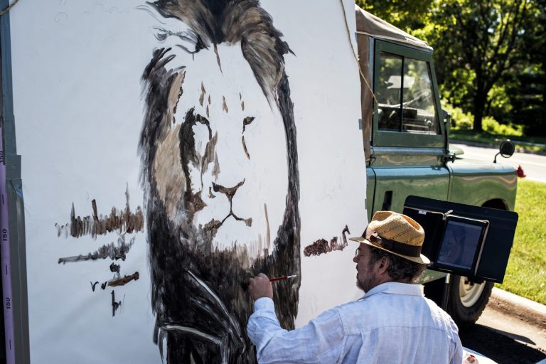 An artist paints a mural of Cecil, a well-known lion killed by Minnesota dentist Walter Palmer during a guided bow hunting trip in Zimbabwe, as part of a silent protest outside Palmer's office in Bloomington, Minn., Wednesday. (Glen Stubbe/Star Tribune via AP)