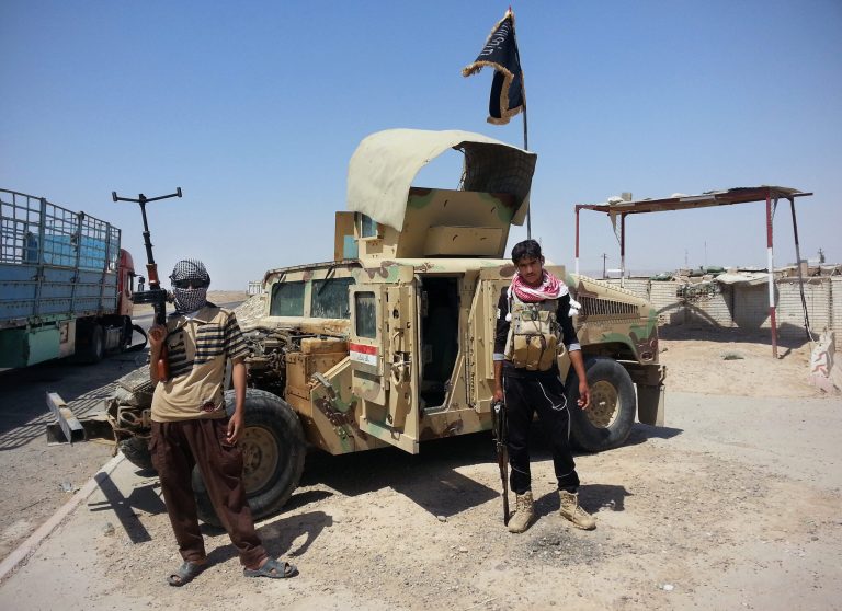 Islamic State group militants stand with a captured Iraqi army Humvee at a checkpoint outside Beiji refinery, some 155 miles north of Baghdad, Iraq. (AP Photo, File)