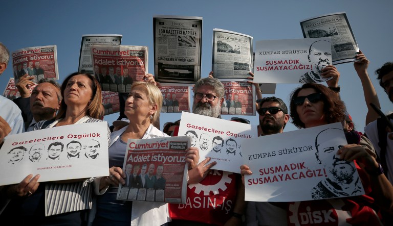 Protesters hold copies of the Cumhuriyet newspaper with headlines in Turkish reading: 'We want justice