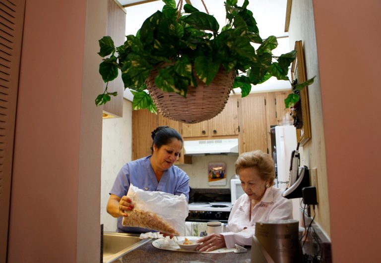 FILE - In this Sept. 3, 2010 file photo, United Home Care Services home health aide Maria Fernandez, left, pours cereal for Herminia Vega, 83, right, as she performs household chores for Vega and her husband, in Miami. On average, nearly 70 percent of people who turn 65 years-old will eventually need some form of long-term care, according to the U.S. Department of Health & Human Services.  (AP Photo/Lynne Sladky)
