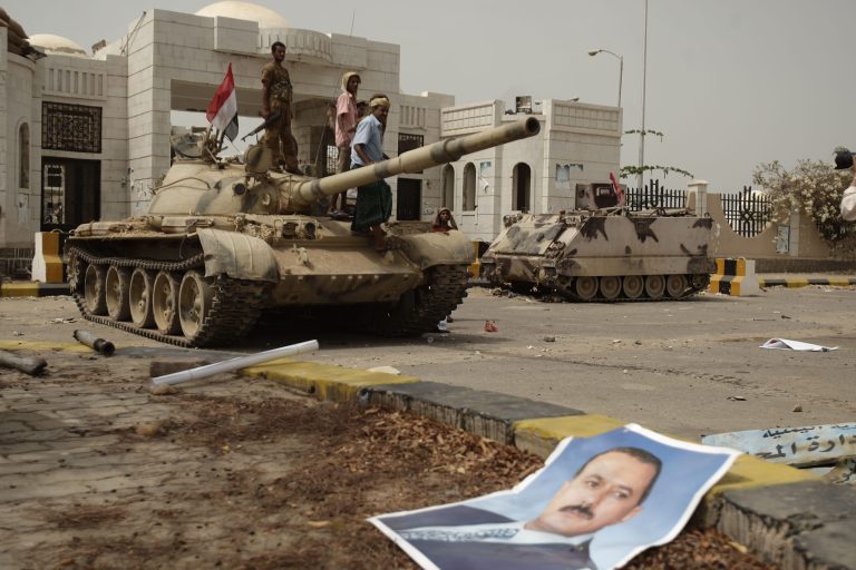   A poster of Yemen's former President Ali Abdullah Saleh lies on the ground as army soldiers and tribesmen loyal to the army gather on a tank in front of the local authority compound in the city of Zinjibar, Yemen after they retook the city from al-Qaida militants, Thursday, June 14, 2012. Airstrikes and clashes intensified in southern Yemen on Wednesday as army troops followed major victories with more pressure on al-Qaida militants holding small towns, according to tribal and military officials. The attacks came a day after Yemeni forces regained control of two major al-Qaida strongholds, Jaar and Zinjibar, which were in the hands of the militants for more than a year. (AP Photo/Hani Mohammed)  