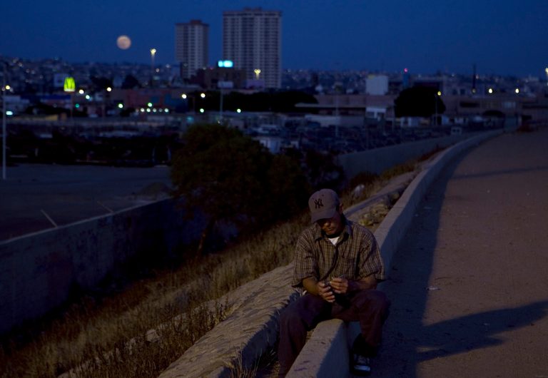 A deported migrant sits on the levee near the Tijuana River basin on the Mexican side of the U.S.-Mexico border, in Tijuana, Mexico, Saturday, Aug. 16, 2008. (AP Photo)Â 