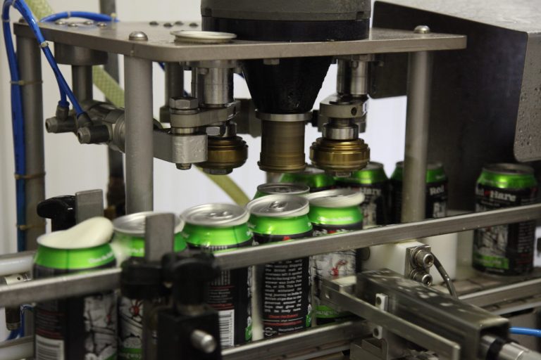 In this July 22, 2104 photo, Red Hare Brewing Company beer cans enter the lid securing stage of canning at the microbrewery's canning facility in Marietta, Ga. The Atlanta-based aluminum manufacturer Novelis Inc. has teamed up with the Marietta, Ga. microbrewery to introduce the first certified recycled beer can with not less than 90 percent recycled content. (AP Photo/Johnny Clark)