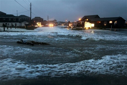 Ocean water rolls over state highway NC 12 in Buxton, N.C., on Hatteras Island at dawn on Sunday, Oct. 28, 2012, as Hurricane Sandy works its way north, battering the U.S. East Coast. (AP Photo/The Virginian-Pilot, Steve Earley)