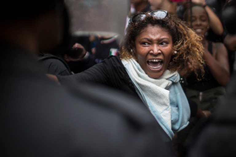 A woman shouts at police officers as residents of Pavao-Pavaozinho slum clash with riot police during a protest against the death of Douglas Rafael da Silva Pereira after his burial in Rio de Janeiro, Brazil, Thursday, April 24, 2014. The protest followed the burial of Douglas Pereira, whose shooting death sparked clashes Tuesday night between police and residents of the Pavao-Pavaozinho slum. (AP Photo/Felipe Dana)