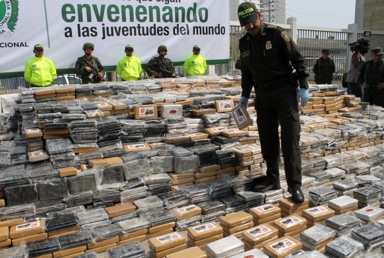 Colombia National Police Chief, Gen. Rodolfo Palomino walks on seized packages of cocaine displayed for the press at a police base in the Caribbean seaport of Cartagena, Colombia, Thursday, April 10, 2014. Police say they seized about 7 tons of cocaine Wednesday in a container bound for the Netherlands' port of Rotterdam. (AP Photo/Felipe Caicedo)
