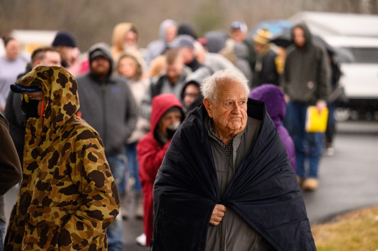 George Rockenberger, 84, tries to stay warm as snow falls on the nearly 150 people waiting in line for the Norfolk Southern Family Assistance Center to open on February 17, 2023 at the Abundant Life Church in New Waterford, Ohio. Residents who qualify can receive a $1000 payment as well as reimbursement to cover costs related to the evacuation from Norfolk Southern.   
