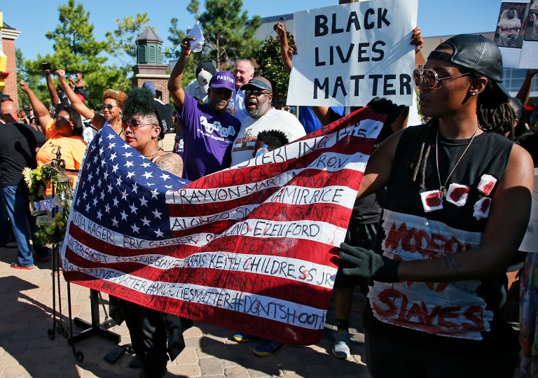 April Watts, left, and Tyler Watts, right, of Oklahoma City, hold a flag with the names of victims of violence printed on it, during a Black Lives Matter rally in Oklahoma City, Sunday, July 10, 2016. (AP Photo/Sue Ogrocki)