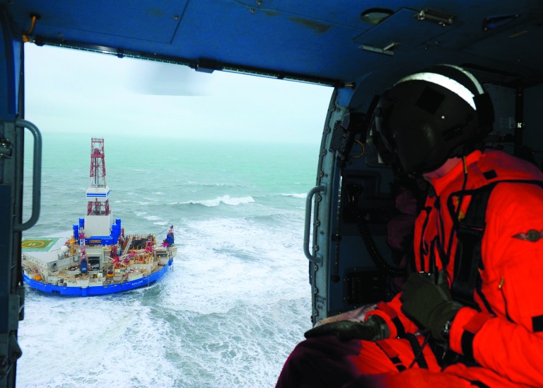 This aerial image provided by the U.S. Coast Guard shows Rear Adm. Thomas Ostebo, Incident Management Team commander, observing the Royal Dutch Shell drilling rig Kulluk aground during an overflight off a small island near Kodiak Island Tuesday Jan. 1, 2013. No leak has been seen from the drilling ship that grounded off the island during a storm, officials said Wednesday, as opponents criticized the growing race to explore the Arctic for energy resources. (AP Photo/U.S. Coast Guard, Sara Francis)