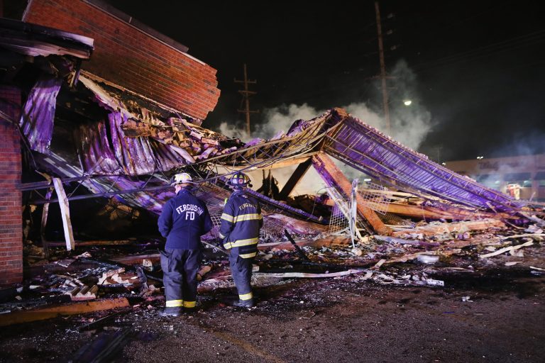 Ferguson firefighters survey rubble at a strip mall that was set on fire when rioting erupted following the grand jury announcement in the Michael Brown case on November 25. (Getty images/Scott Olson)