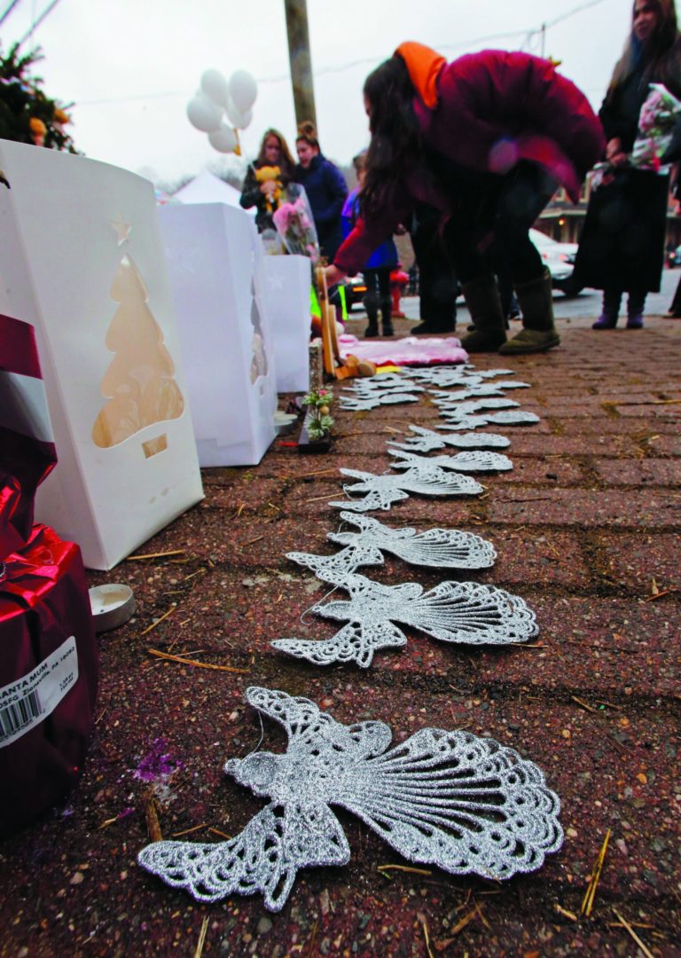A woman lays flowers at the site of a makeshift memorial for school shooting victims at the village of Sandy Hook in Newtown, Conn., Sunday, Dec. 16, 2012. A gunman opened fire at Sandy Hook Elementary School in the town, killing 26 people, including 20 children before killing himself on Friday. (AP Photo/Charles Krupa)