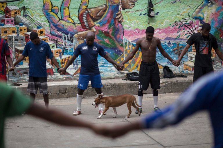 Friends and neighbors of the late Douglas Rafael da Silva Pereira pray before playing soccer in a plaza near the spot where Silva Pereira's body was found in the Pavao Pavaozinho slum of Rio de Janeiro, Brazil, Wednesday, April 23, 2014. On Tuesday night, angry residents who blame police set fires and showered homemade explosives and glass bottles onto a busy avenue in the city's main tourist zone following the killing of the popular local figure. (AP Photo/Felipe Dana)