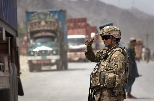 U.S. Army Spc. Laurianne Lau from Stockton, Calif., allows a convoy to pass while directing traffic at the border crossing between Afghanistan and Pakistan on Aug. 27, 2011, at Torkham, Afghanistan. The port of entry is busiest in Afghanistan and the most important for the U.S. military, which imports more than 30 percent of all its supplies and military equipment through Torkham. (Photo by John Moore/Getty Images)