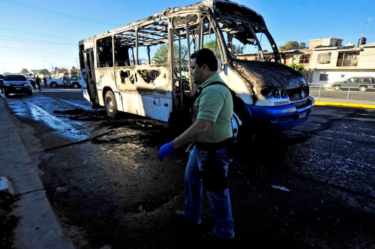 A forensic specialist walks around a burned bus in the town of Zapopan, Mexico, Thursday, Jan. 30, 2014.  The bus was torched by unidentified attackers while officials detained the son of an alleged leader of a drug cartel during a raid in this town. A federal official who was not authorized to be quoted by name says the man detained is Ruben Oseguera. His father Nemesio Oseguera allegedly leads the Jalisco New Generation cartel. (AP Photo)