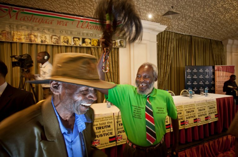 Mau-Mau veteran Mathenge Iregi, 81, waves a a ceremonial whisk to celebrate as he and others await a press conference about an announcement regarding their legal case for compensation against the British Government, in Nairobi, Kenya Thursday, June 6, 2013. The British government is set to announce compensation for Kenyans abused during a rebellion against colonial rule in the 1950s. (AP Photo/Ben Curtis)