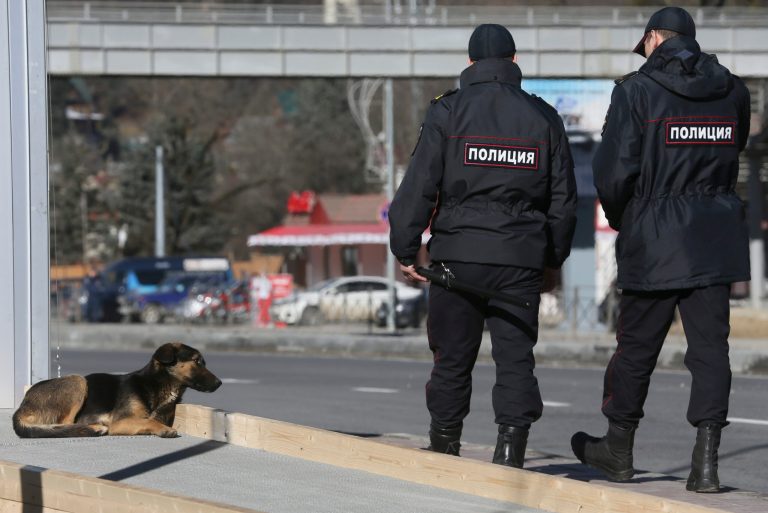 Policemen walk past a stray dog near the Media Center of the 2014 Winter Olympics, Monday, Feb. 3, 2014, in Krasnaya Polyana, Russia.(AP Photo/Dmitry Lovetsky)