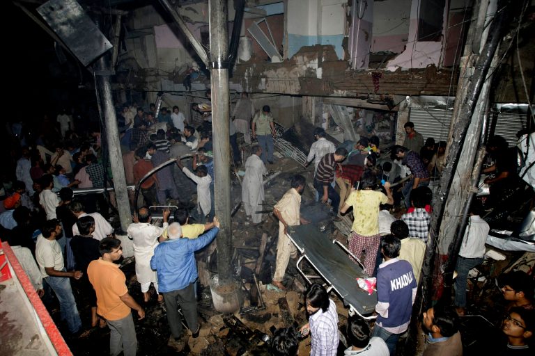 Pakistani medics and civilians gather at the site of a bomb blast in Karachi, Pakistan, Sunday, March 3, 2013. Pakistani officials say a bomb blast has killed dozens of people in a neighborhood dominated by Shiite Muslims in the southern city of Karachi. (AP Photo/Fareed Khan)