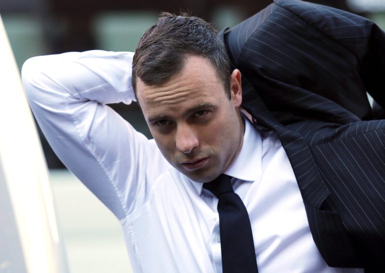 Oscar Pistorius puts on his jacket as he arrives at the high court in Pretoria, South Africa, Friday, April 11, 2014. The chief prosecutor laughed scornfully at an answer from Pistorius during the Olympic athlete's murder trial Thursday, mocking the man who shot his girlfriend. Pistorius is charged with murder for the shooting death of his girlfriend, Reeva Steenkamp, on Valentine's Day in 2013. (AP Photo/Themba Hadebe)