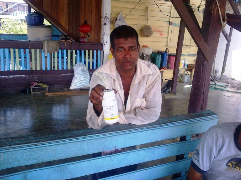 In this Monday, Oct. 6, 2014 photo, Vijai Ramlackhan holds a container of pesticide similar to the type his 17-year-old son used to commit suicide on their farm in the Berbice region of Guyana, a country that the World Health Organization says has the highest rate of suicide in the world. (AP Photo/Bert Wilkinson)