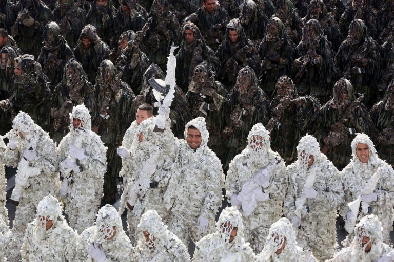 Wearing ghilli suits, Iranian army troops march in a parade as one of them hold up his weapon, marking National Army Day in front of the mausoleum of the late revolutionary founder Ayatollah Khomeini just outside Tehran, Iran, Friday, April 18, 2014. Ahead of the parade Iran's President Hassan Rouhani underscored his moderate policies and outreach to the West in a speech. (AP Photo/Vahid Salemi)