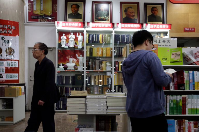 In this photo taken Monday, Oct. 13, 2014, customers walk past portraits of Mao Zedong displayed at a bookstore in Beijing. Authorities in China have ordered books by Chinese-American scholar Yu Ying-shih and several others to be removed from sale, as Beijing expresses its displeasure with writers showing support for pro-democracy movements in Hong Kong and elsewhere, bookstores and publishers said. (AP Photo/Ng Han Guan)