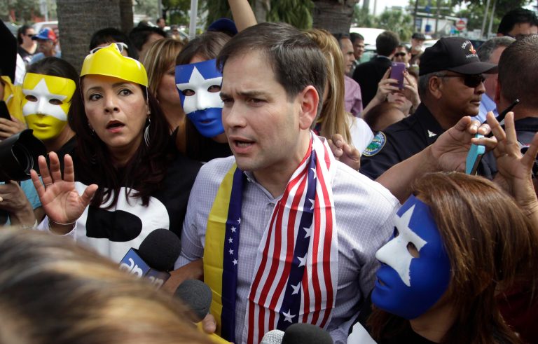 FILE - In this Feb. 28, 2014 file photo, surrounded by mask-wearing supporters of Venezuela's opposition, U.S. Senator Marco Rubio, center, speaks to the media in Doral, Fla. Rubio and Gov. Rick Scott called for sanctions against Venezuela, as opponents of President Nicolas Maduro were staging countrywide protests. Amid escalating tensions with Venezuela, the U.S. State Department on Wednesday, July 30, 2014, announced sanctions against Venezuelan officials it said committed human rights abuses during the spring crackdown on anti-government protests.  (AP Photo/Javier Galeano, File)