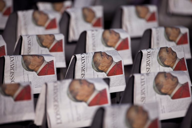 Copies of the Osservatore Romano Vatican newspaper with a photo of Pope Paul VI on the front page are seen over empty chairs prior to the arrival of Pope Francis to celebrate his beatification ceremony and a mass for the closing of of a two-week synod on family issues, in Saint Peter's Square at the Vatican,  Sunday, Oct. 19, 2014. (AP Photo/Andrew Medichini)
