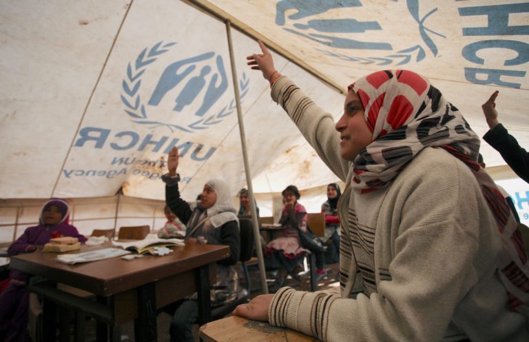 Syrian refugee, Amal Fawwaz, 11, right, raises her hand to answer her teacher's question in a makeshift tent class at an unofficial refugee camp on the outskirts of Amman, Jordan. (AP/Mohammad Hannon)