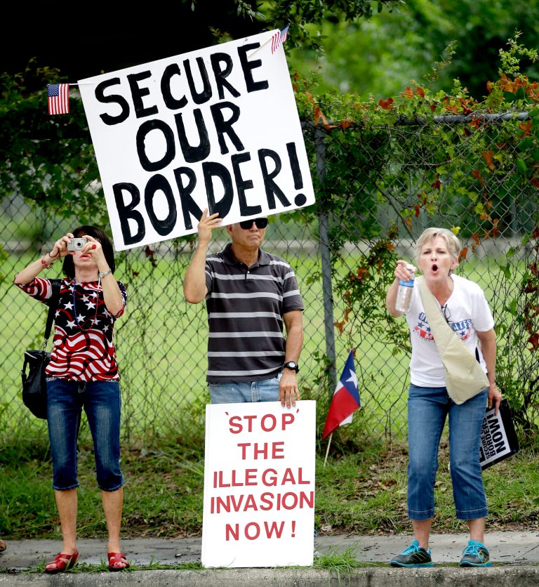 Demonstrators hold signs and yell outside the Mexican Consulate Friday, July 18, 2014, in Houston. (AP Photo/David J. Phillip)