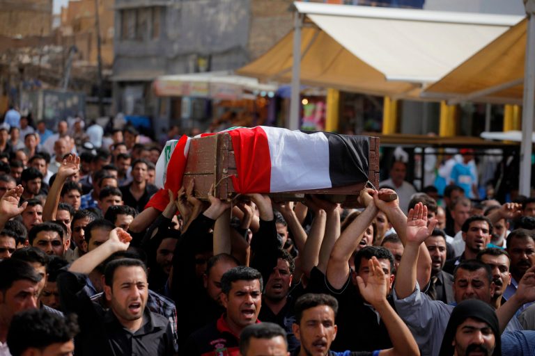 Mourners chant slogans against the al-Qaida breakaway group Islamic State of Iraq and the Levant (ISIL), while carrying a flag-draped coffin of Ahmed Marzouk an Iraqi officer who was killed, said his family, in a fake checkpoint on Thursday, during his funeral procession in the Shiite holy city of Najaf, 100 miles (160 kilometers) south of Baghdad, Iraq, Friday, May 16, 2014. Bombings and shootings around Iraq's capital, including a deadly attack involving militants using a fake checkpoint to target army officers, killed and wounded dozens of people on Thursday, officials said. (AP Photo/ Jaber al-Helo)