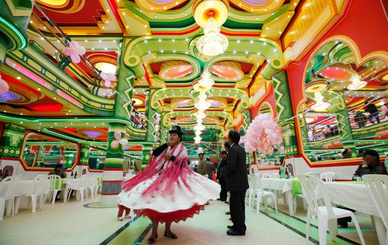 In this May 17, 2014 photo, an Aymara woman dances in a ballroom, part of the newfangled minimansions rising up in El Alto, Bolivia. They attest to a new class of indigenous nouveau riche, many of them merchants who converted street stalls into fortunes. Owners often sink a million dollars into the opulent edifices.  (AP Photo/Juan Karita)