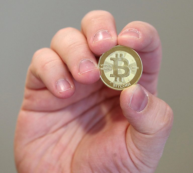 Software engineer Mike Caldwell shows the front of a physical Bitcoin he minted in his shop in Sandy, Utah. (George Frey/Getty Images)