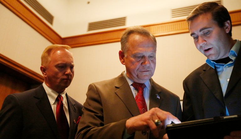 U.S. Senate candidate Roy Moore, center, looks at election returns with staff during an election-night watch party at the RSA activity center, Tuesday, Dec. 12, 2017, in Montgomery, Ala. (AP Photo/Brynn Anderson)
