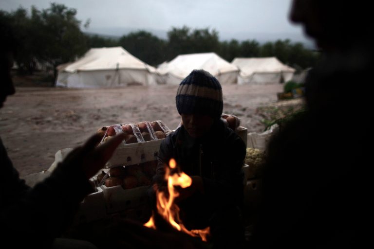   Syrians, who fled their homes with their families, gather around a fire to warm themselves at a makeshift vegetables store in a camp for the displaced in the village of Atmeh, Syria, Tuesday, Dec. 18, 2012. (AP Photo/Muhammed Muheisen)  