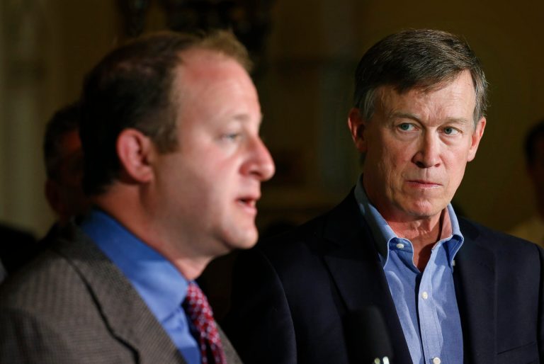 Colo. Gov. John Hickenlooper, right, listens as U.S. Rep. Jared Polis, D-Colo., takes questions during a news conference about fracking, at the Capitol, in Denver, Monday, Aug. 4, 2014. During the news conference Hickenlooper announced the creation of a task force charged with crafting recommendations to help minimize land use conflicts that can occur when siting oil and gas facilities near homes, schools, businesses and recreational areas. (AP Photo/Brennan Linsley)
