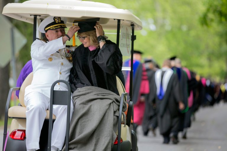 Former U.S. Rep. Gabrielle Giffords leans forward as her husband, retired space shuttle Commander Mark Kelly, adjusts her mortarboard as they ride in the procession for the 153rd Commencement at Bard College, Saturday, May 25, 2013, in Annandale-on-Hudson, N.Y. They delivered the commencement address, and Giffords received an honorary degree. (AP Photo/Philip Kamrass)