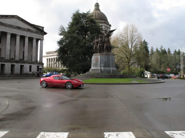 A Tesla car drives near the Washington state Capitol on Monday, Feb. 17, 2014, in Olympia, Wash. The electric car company, which has sales and service operations in Seattle and Bellevue, held a rally to protest measures being considered by the Legislature that would prevent it from opening additional facilities in the state. (AP Photo/Rachel La Corte)