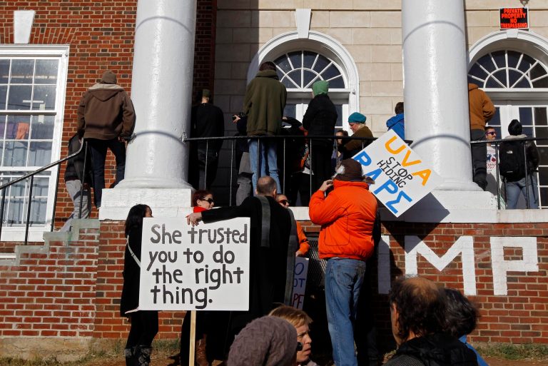 People gather with signs during a protest at the front porch of the Phi Kappa Psi fraternity house at the University of Virginia in Charlottesville. The University of Virginia on Saturday suspended activities at all campus fraternal organizations amid an investigation into a published report in which a student described being sexually assaulted by seven men at a fraternity in 2012. (AP Photo/The Daily Progress, Ryan M. Kelly)