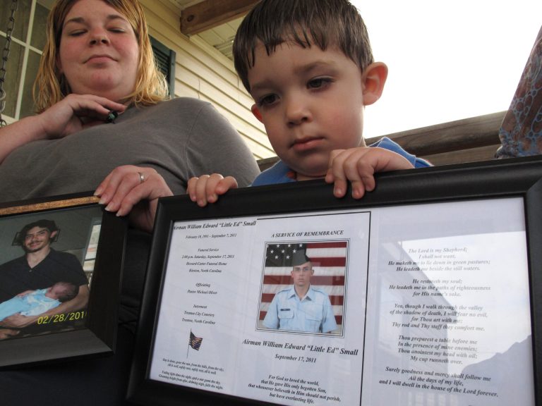 FILE - In this March 18, 2013, file photo, Shane Mercer holds a photo of his father, Airman Will Small, as his mother Alecia Mercer looks on at their home in Kinston, N.C. Small, whose organs were donated to four patients after he died, had at least two untreated raccoon bites several months before he became sick, and tests confirm his rabies-infected kidney led to a Maryland recipient's death. An article in the March 27 issue of Zoonoses and Public Health says social media played an invaluable role in the investigation, allowing officials to find someone who was seated next to the infected donor on a commercial flight in 2011. That person was assessed and not recommended for the shots. (AP Photo/Allen Breed, File)