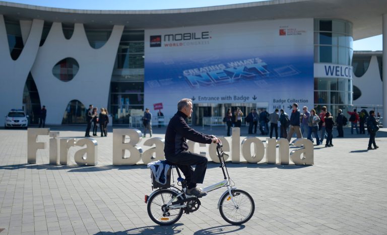 A man rides his bicycle outside  the Mobile World Congress, the world's largest mobile phone trade show in Barcelona, Spain, Sunday, Feb. 23, 2014. (AP Photo/Manu Fernandez)
