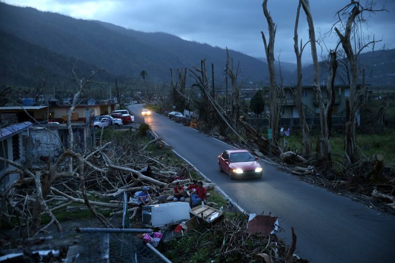 Neighbors sit on a couch outside their destroyed homes as sun sets in the aftermath of Hurricane Maria, in Yabucoa, Puerto Rico, Tuesday, Sept. 26, 2017. (AP Photo/Gerald Herbert)