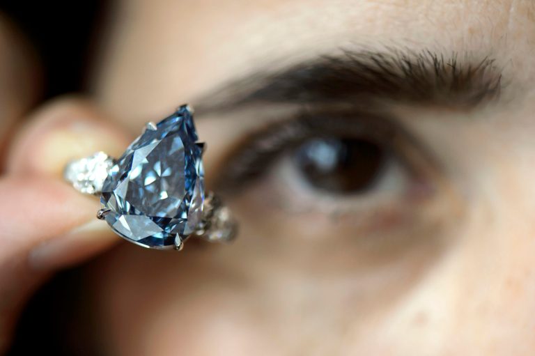 FILE - In this May 9, 2014 file picture a Christie's employee holds a 13.22 carat diamond called 'The Blue', the largest flawless vivid blue diamond yet found, which is estimated to sell between US dlrs  21 to  25 million ,  during a preview at Christie's, in Geneva, Switzerland.   The auction will take place on Wednesday May 14, 2014 evening  in Geneva. (AP Photo/Keystone, Martial Trezzini,file)
