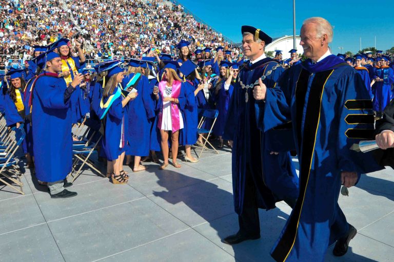 Vice President Joe Biden, right, is escorted to the stage to speak at the University of Delaware's commencement ceremony in Newark, Del., Saturday, May 31, 2014. Biden, who graduated from UD in 1965, told the graduating class that they are stepping into a rapidly changing world that presents profound dangers and challenges as well as incredible opportunities.  (AP Photo/Emily Varisco)