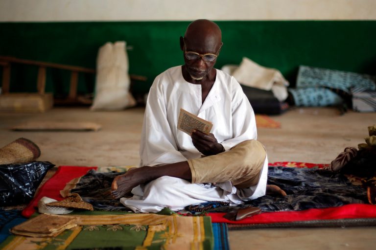 Marabou Husein Aba Ali reads prayers at the mosque at PK12, the last checkpoint at the exit of the town, Tuesday Feb. 11, 2014, where he and 3500 other Muslims have sought refuge from sectarian violence, awaiting for transport from Bangui, Central African Republic, to neighboring Chad. (AP Photo/Jerome Delay)