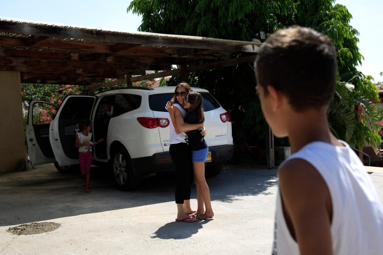 Shiri Medina, center left, hugs her daughter Yael, as they returned home a month after they fled to different locations, in Netiv Haasara near the Israel Gaza border on Wednesday, Aug. 6, 2014. With a cease-fire taking hold, residents of southern Israel slowly begin trickling back to hometowns that largely emptied out during a monthlong war against Hamas militants in the neighboring Gaza Strip. (AP Photo/Tsafrir Abayov)