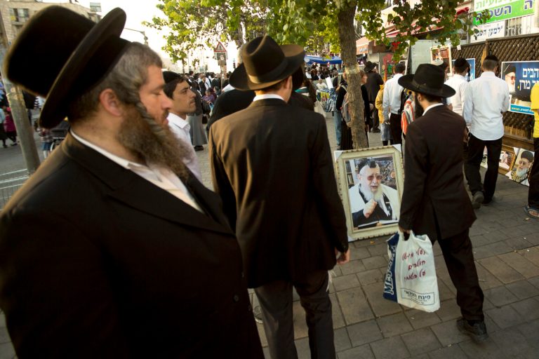 File - In this Oct. 13, 2013 file photo, ultra-Orthodox Jewish men walk past a picture of the late religious spiritual leader of Israel's Sephardic Jews, Rabbi Ovadia Yosef, at a ceremony a week after his funeral in Jerusalem. The Spanish conservative government, which enjoys an absolute majority in Parliament, plans to make amends in weeks to come with a law that offers citizenship to the legions of Jews forced to flee Spain in 1492. (AP Photo/Sebastian Scheiner, File)