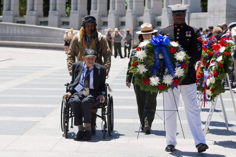 World War II veteran Henry Mendoza, seated, of Rancho Cucamonga, Calif., is pushed by National Park Service historian John McCaskill as they lay a wreath during a ceremony to mark the 70th anniversary of the D-Day landings, Friday, June 6, 2014, at the World War II Memorial in Washington. (AP Photo/ Evan Vucci)